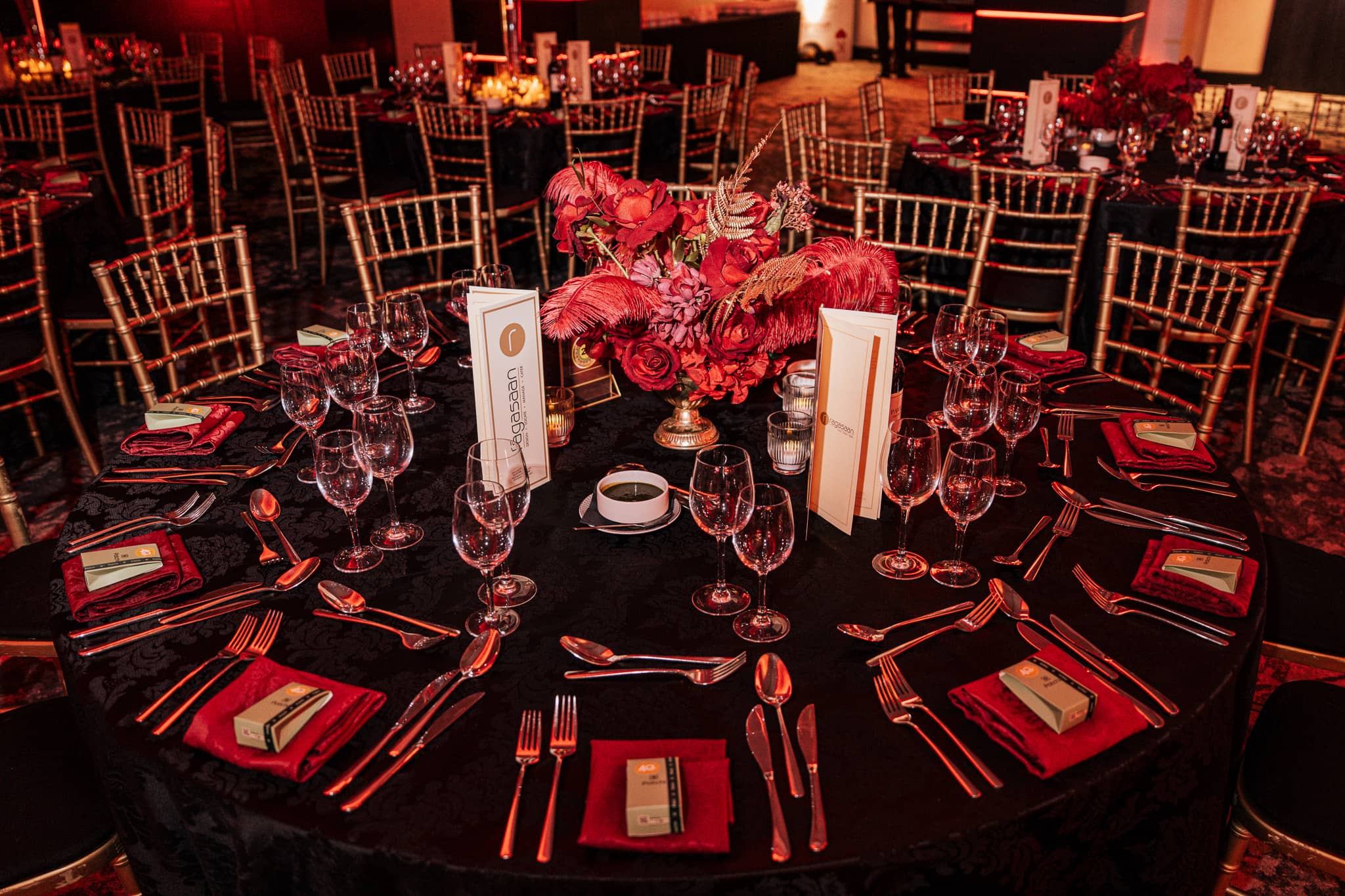 A dressed dinner table with red floral centrepiece, gold chairs and warm lighting, at Brightsun Travel’s 40th anniversary at InterContinental London Park Lane.