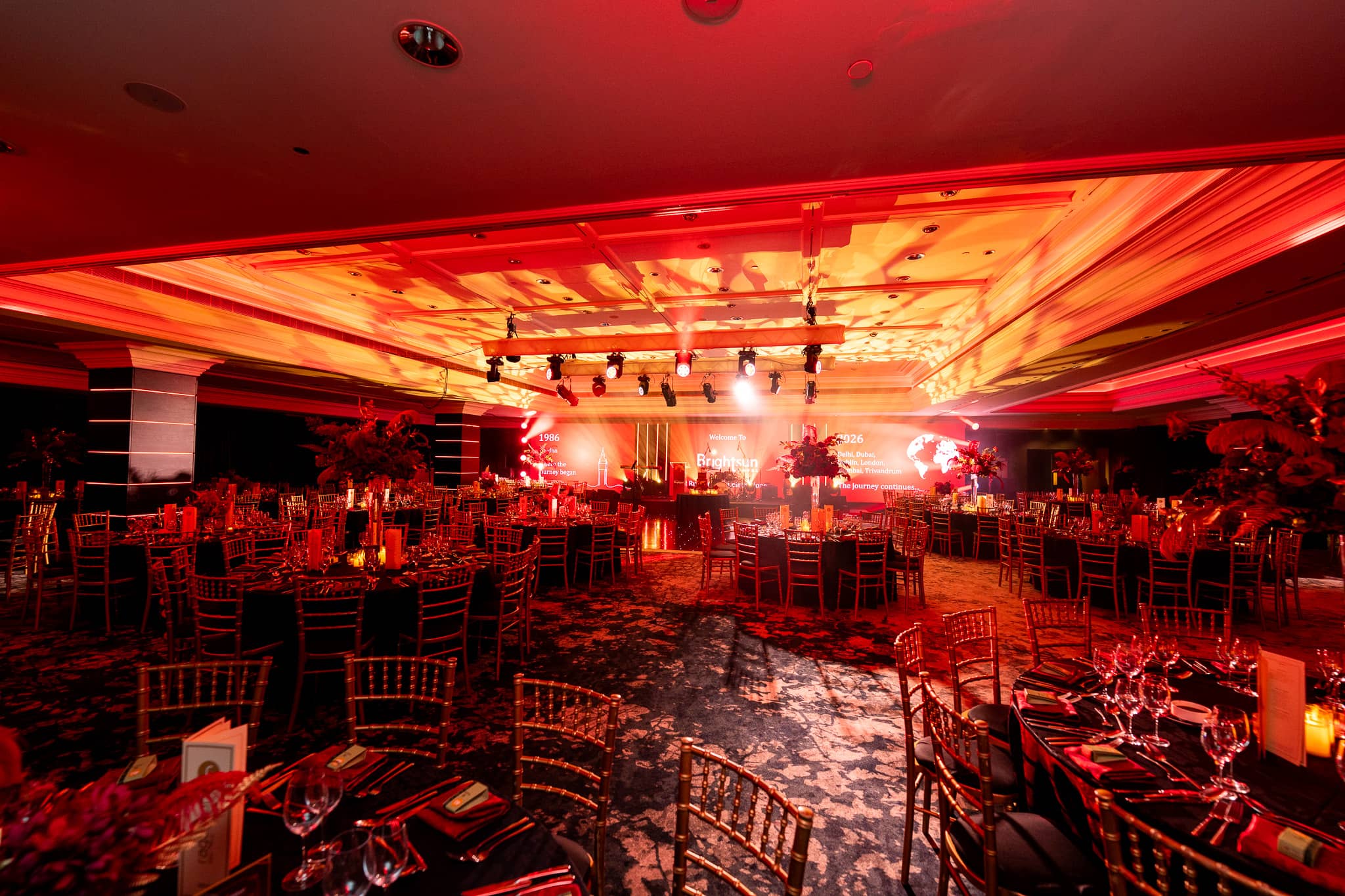 The ballroom ceiling filled with gold patterns above dinner tables and the stage, at Brightsun Travel’s 40th anniversary at InterContinental London Park Lane.