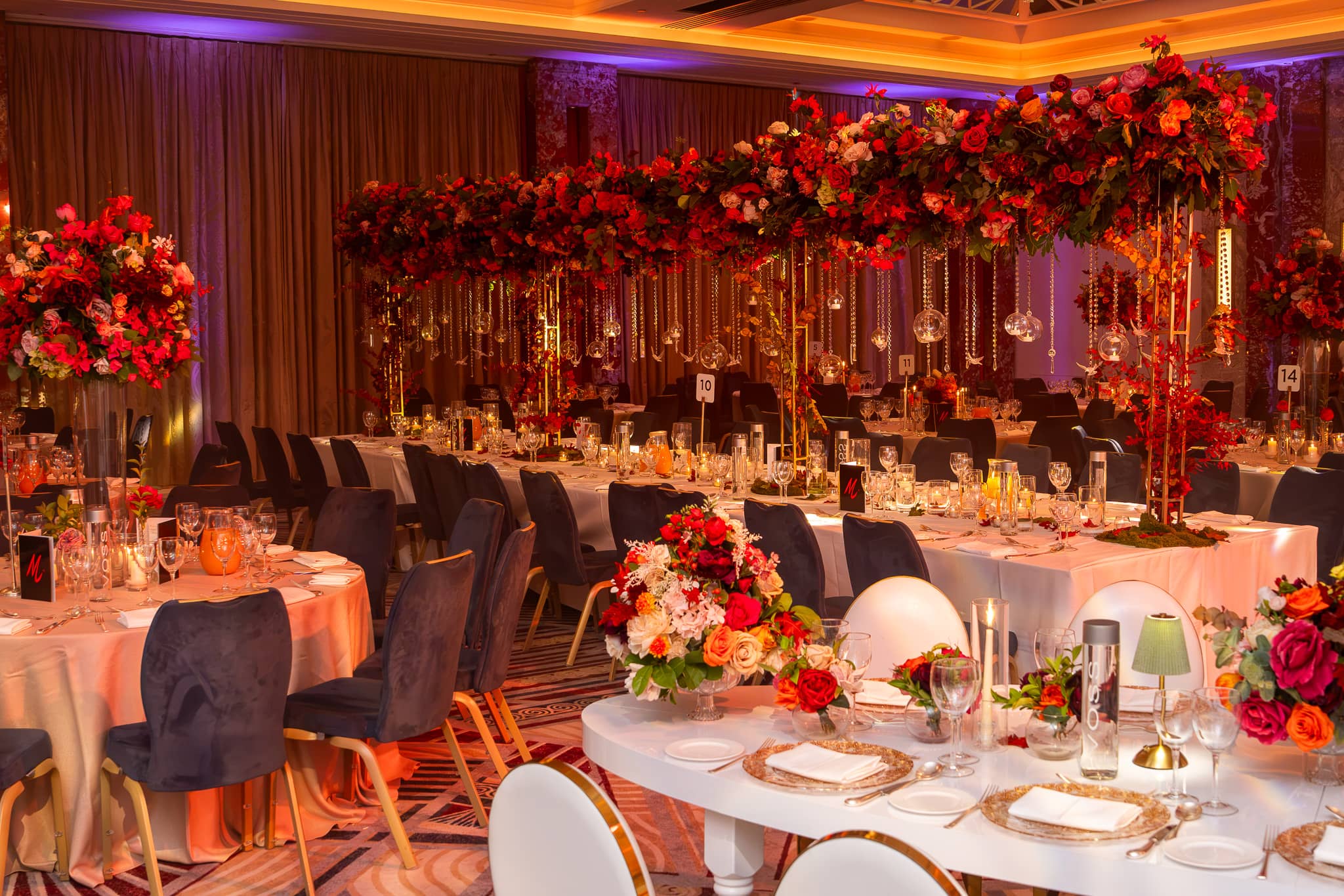 Long and curved dining tables under amber and purple light at Royal Lancaster London.