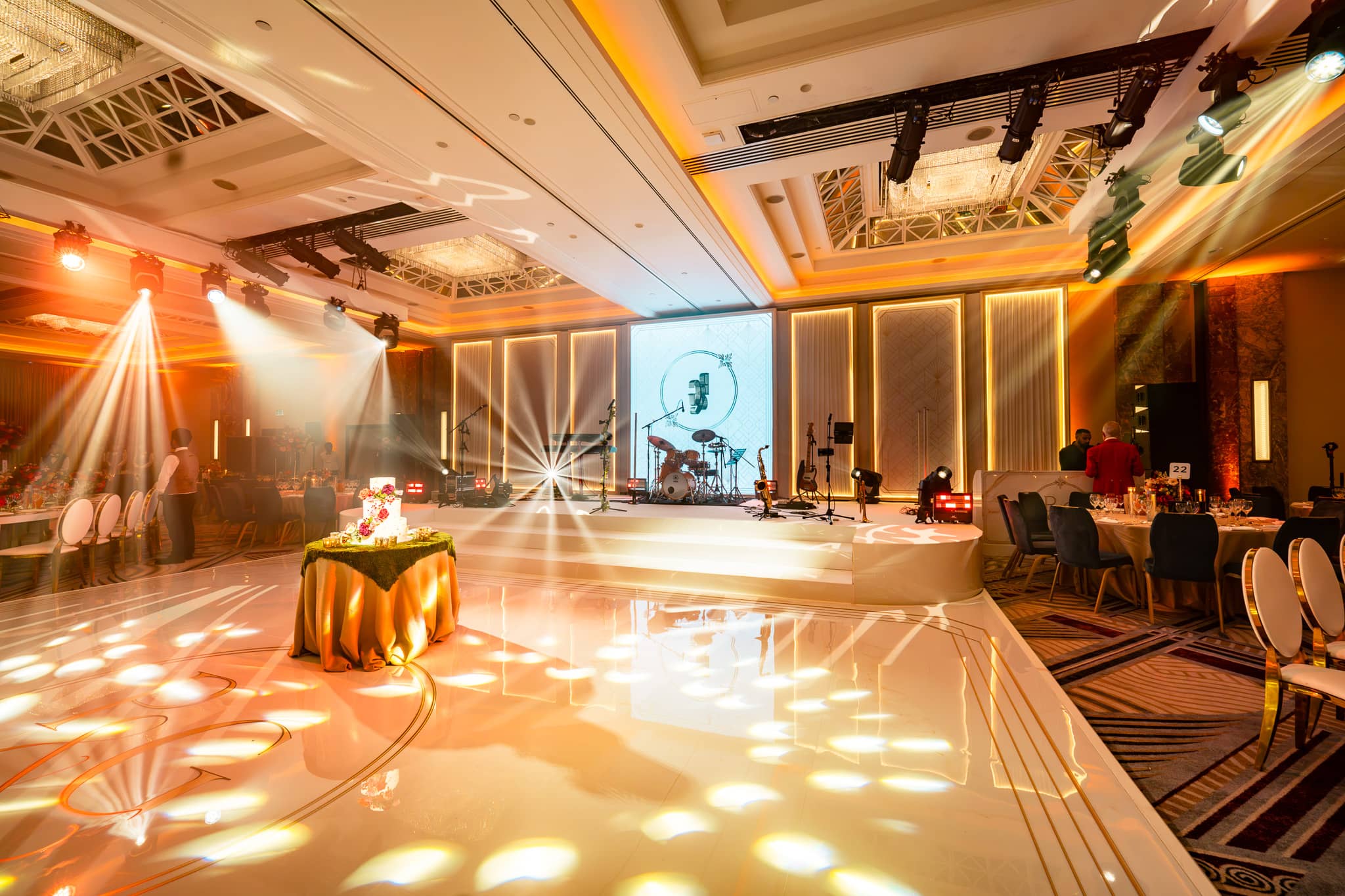 Patterned white light across Pooja and Gary’s bespoke dancefloor with the illuminated stage behind.