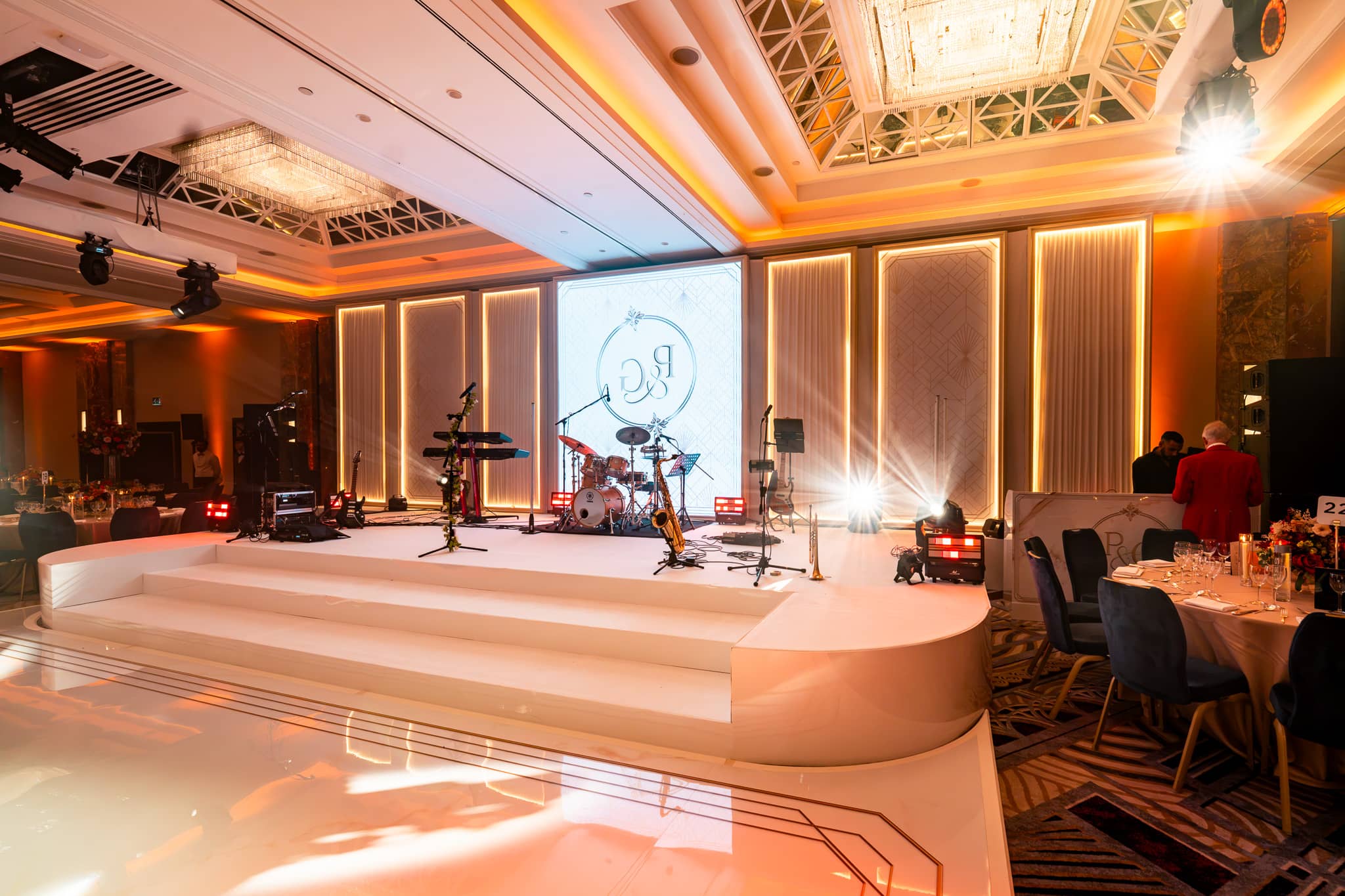 Curved white stage ends and broad steps in front of illuminated set panels and the central LED screen.