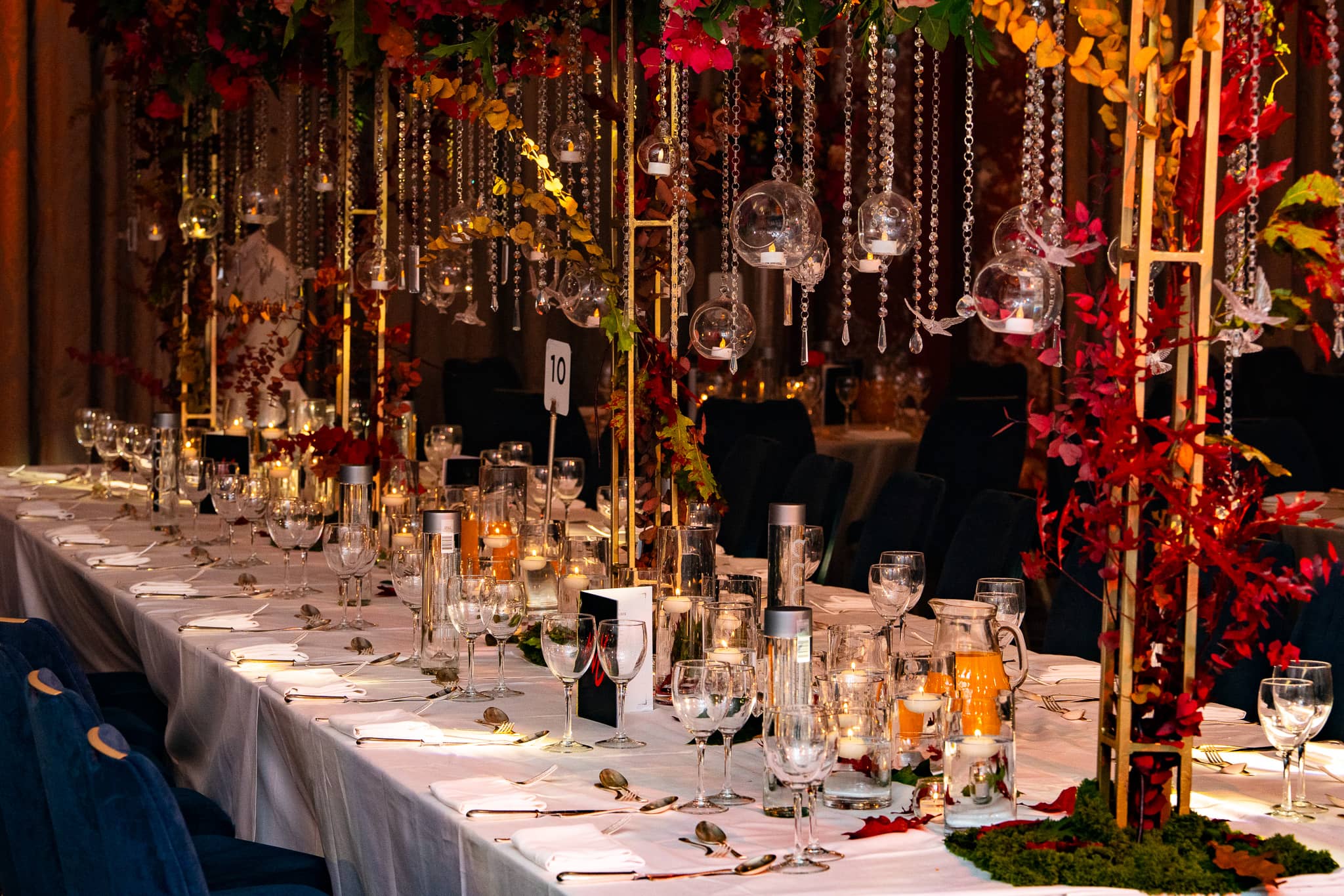 Long dining table with hanging candle holders and red floral arrangements at Royal Lancaster London.