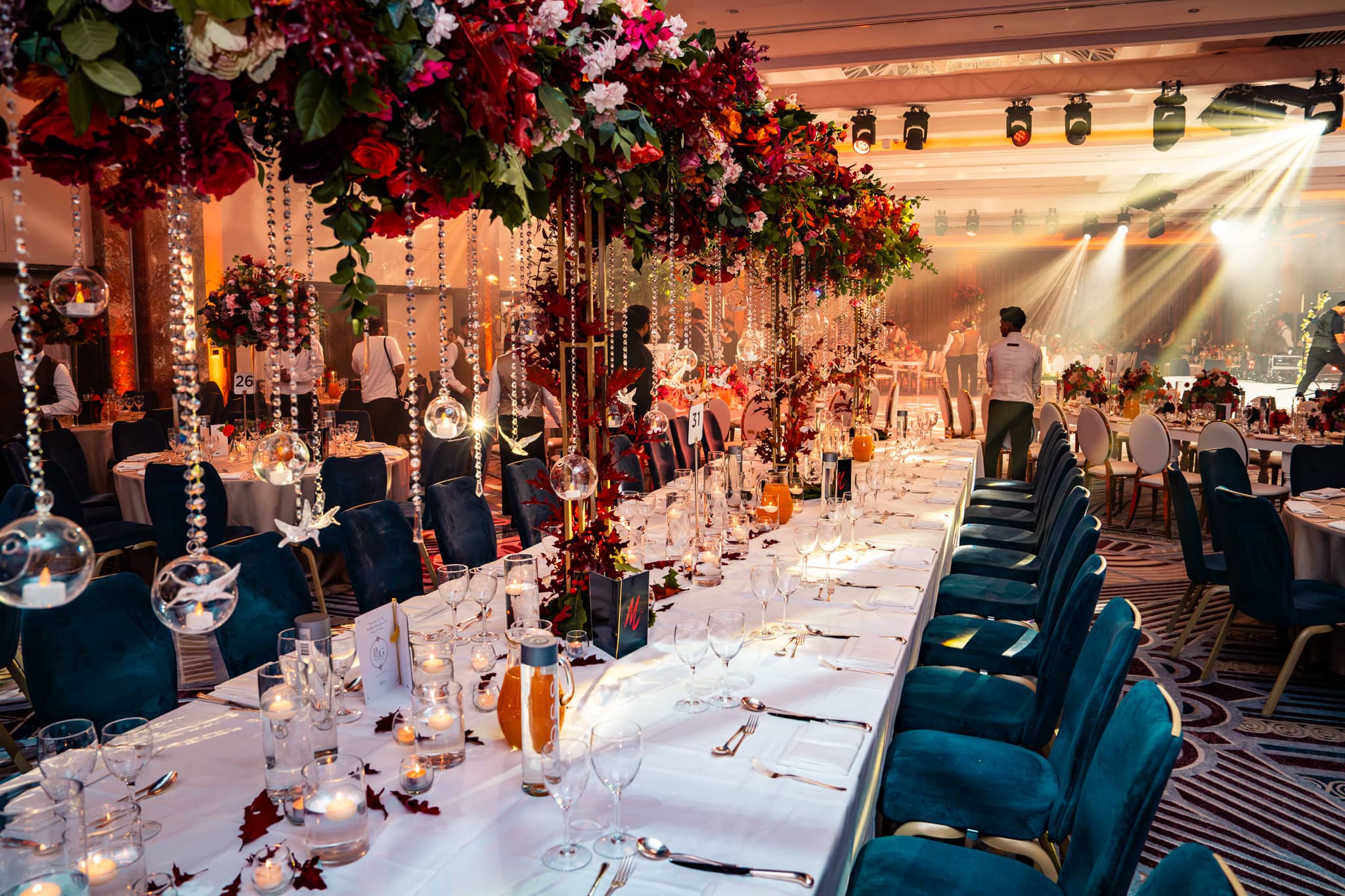 View along a long banquet table towards the bright stage lighting at Royal Lancaster London.