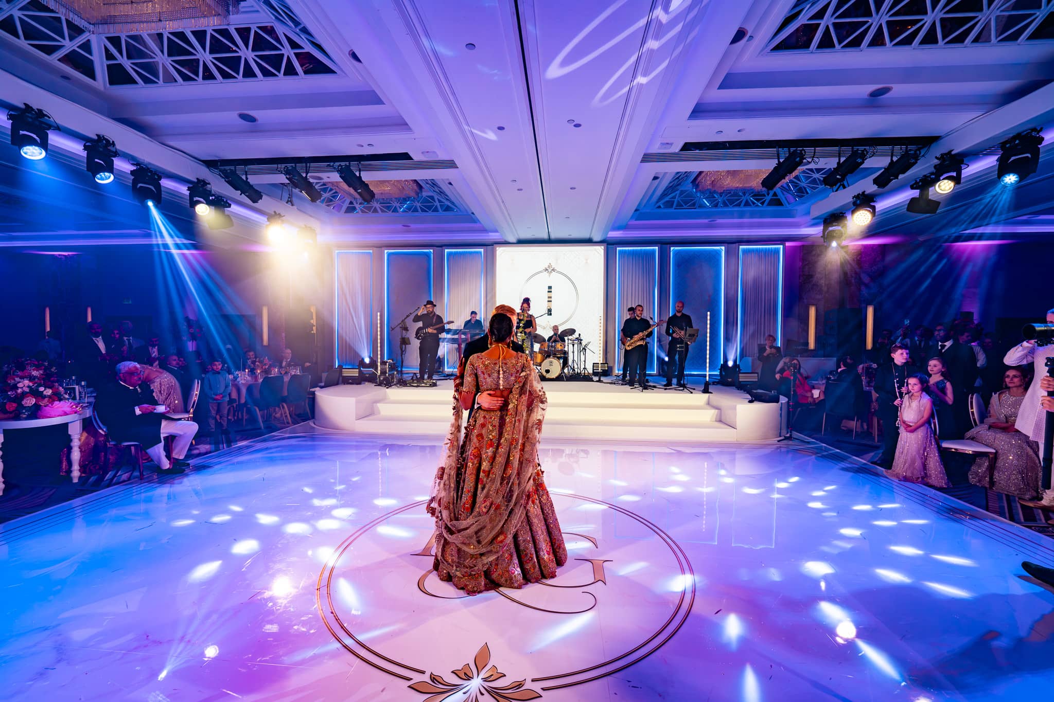 Wide ballroom view of Pooja and Gary’s first dance under purple and blue lighting.