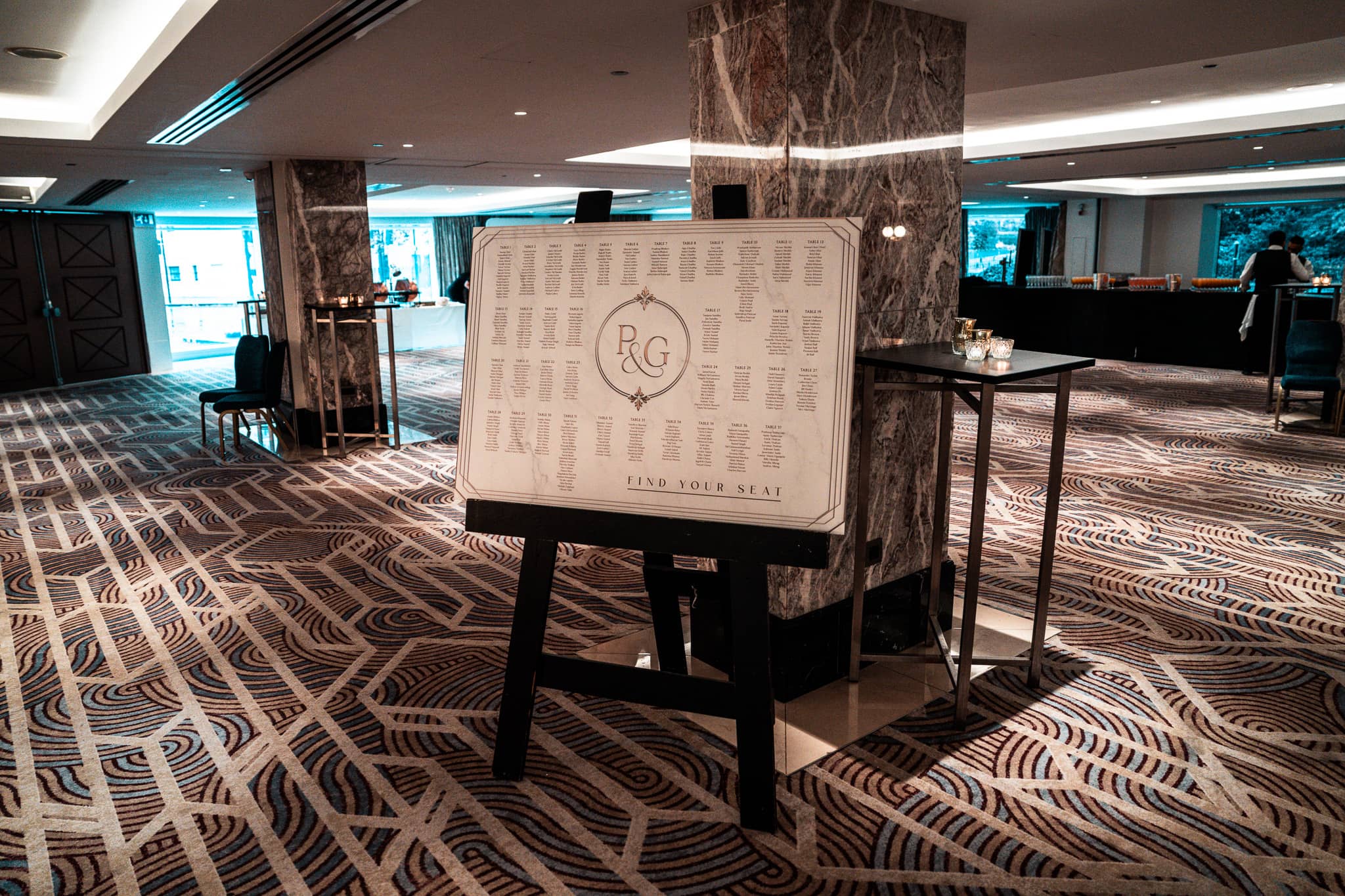 Printed seating plan with Pooja and Gary’s monogram displayed in the Royal Lancaster London foyer.