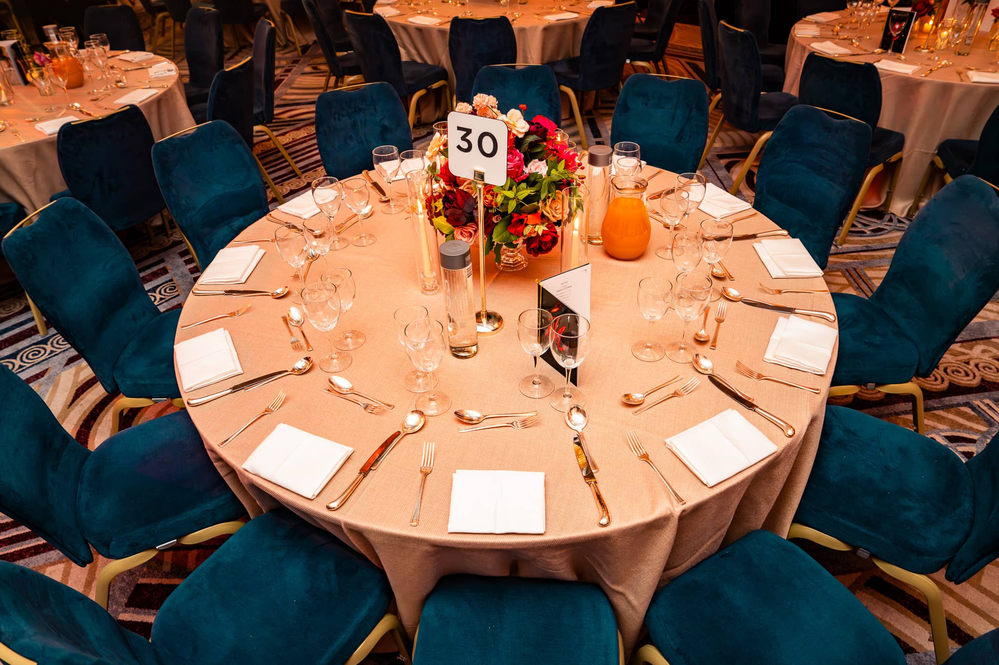 Round guest table with blue chairs, place settings and a floral centrepiece at Royal Lancaster London.
