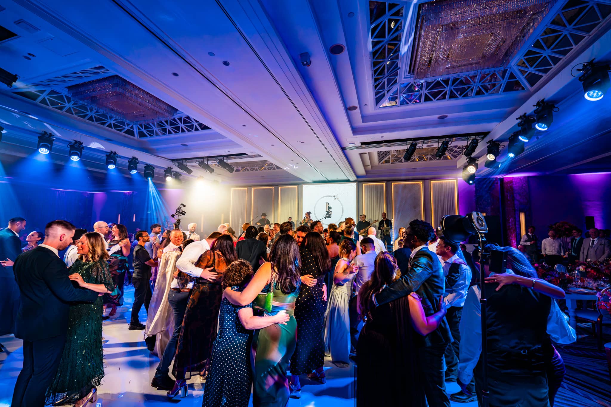 Wedding guests dancing beneath blue and purple overhead lighting at Royal Lancaster London.