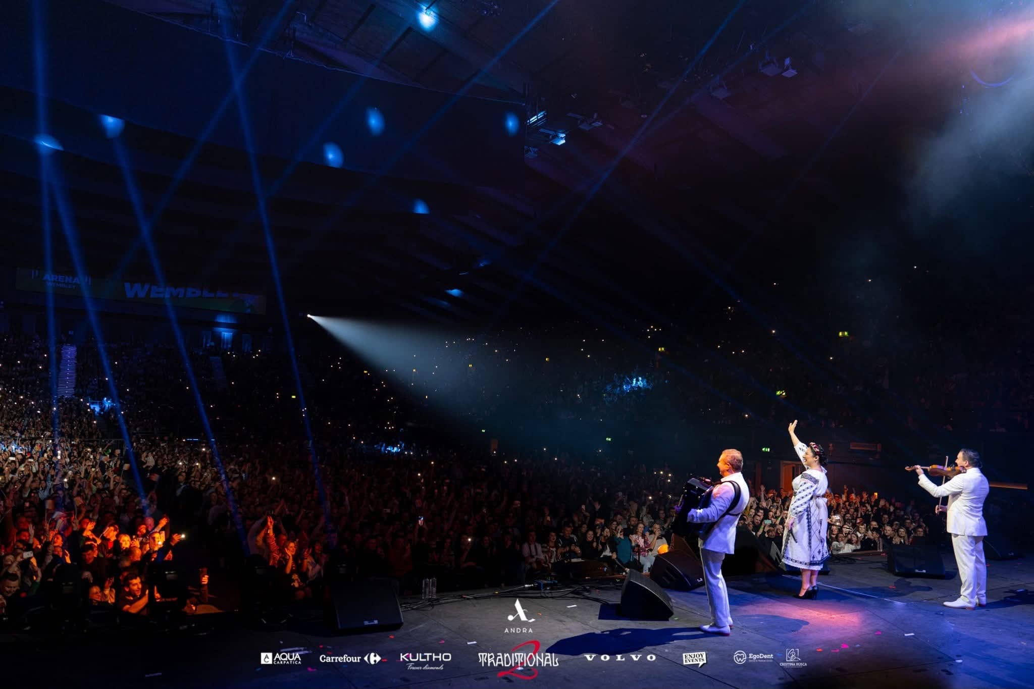 Andra with violin and accordion at the front of stage, Wembley signage and a full arena behind them, Andra Traditional 2 at OVO Arena Wembley, production by Kudos AV.
