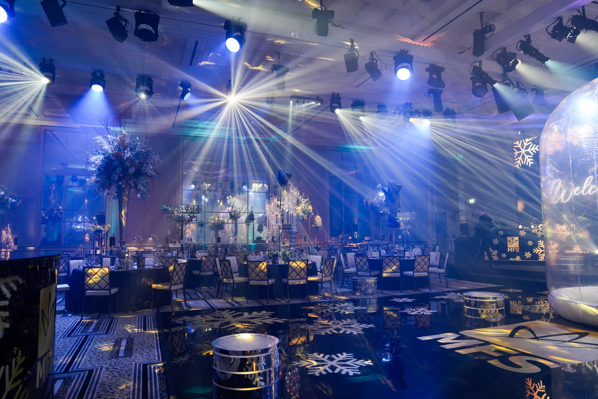 White beams cross blue-lit dinner tables beside the MFS printed dancefloor at The Peninsula London