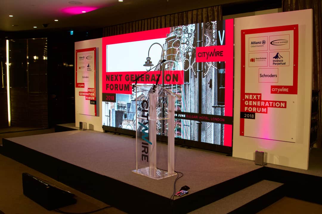 A branded conference set with stage graphics and screens by Kudos AV