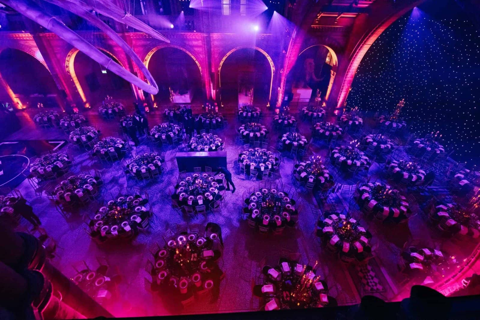 Kudos 10 at the Natural History Museum, banquet tables and floral centrepieces under a starfield ceiling, by Kudos AV