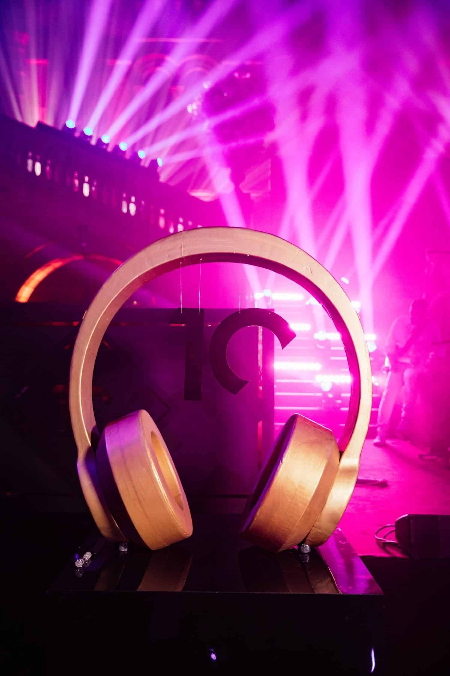 Kudos 10 at the Natural History Museum, branded gold headphones prop in pink haze, by Kudos AV