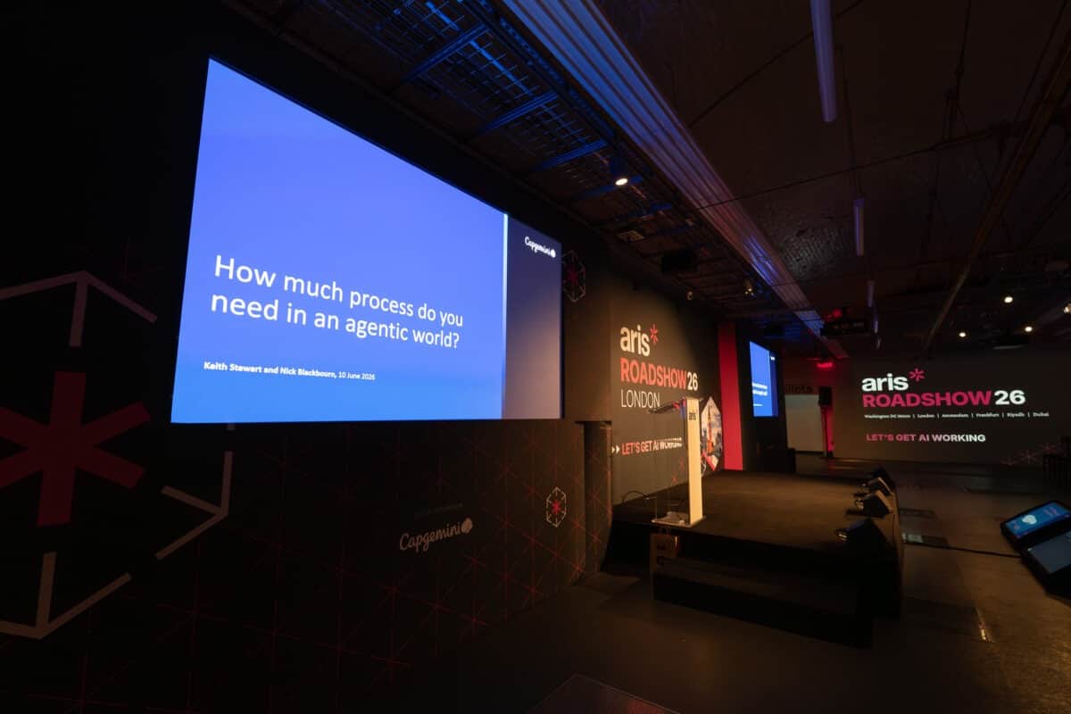 A corporate conference set with presentation screens and stage lighting, produced by Kudos AV