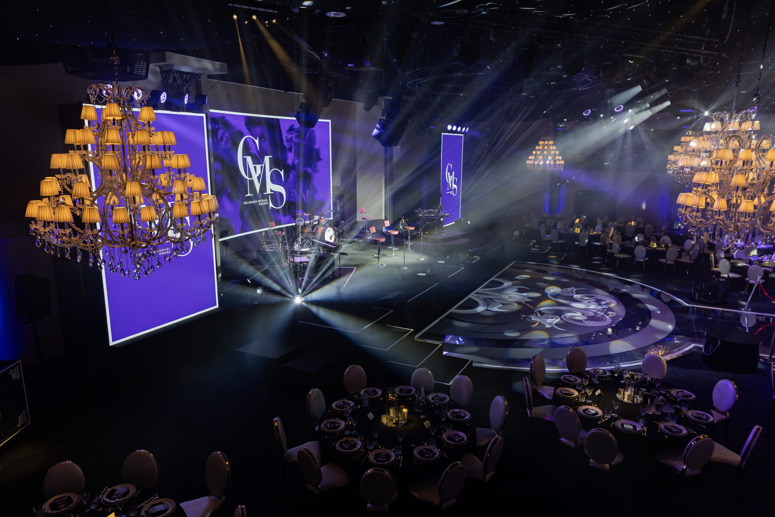 Elevated view of the stage at The George Michael Singers Live, IXL Events Centre: 42ft band stage, three LED screens with GMS branding, bespoke curved printed dancefloor and circular bar, Kudos AV